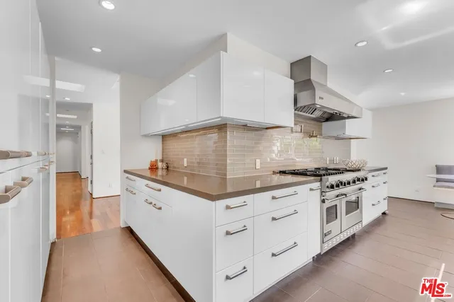 a view of a patio with couches table and chairs under an umbrella with wooden floor