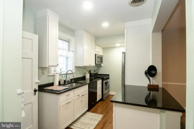 a kitchen with granite countertop white cabinets and a sink