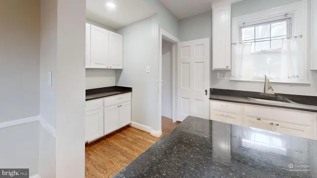 a kitchen with granite countertop white cabinets and a sink