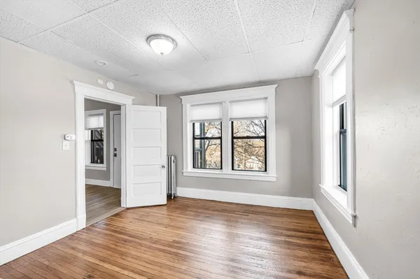 an empty room with wooden floor and windows