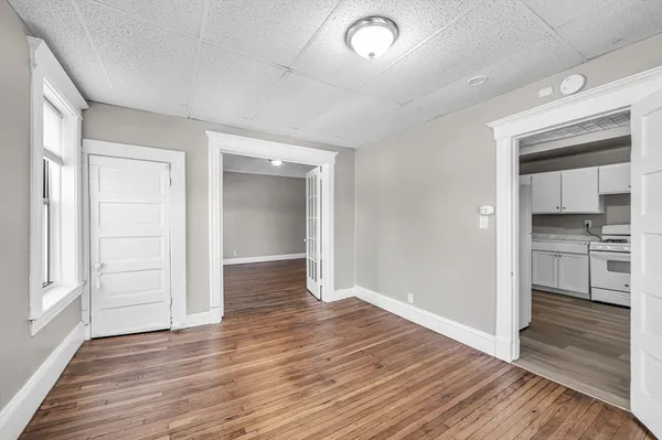 an empty room with wooden floor cabinet and windows