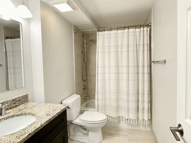 a bathroom with a granite countertop sink toilet and shower