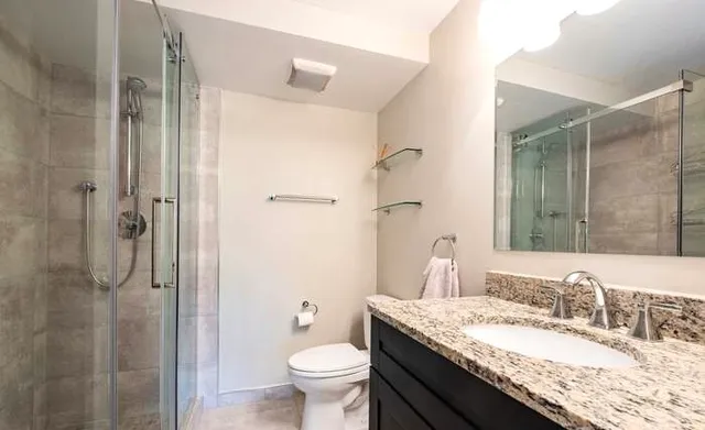 a bathroom with a granite countertop sink toilet and shower