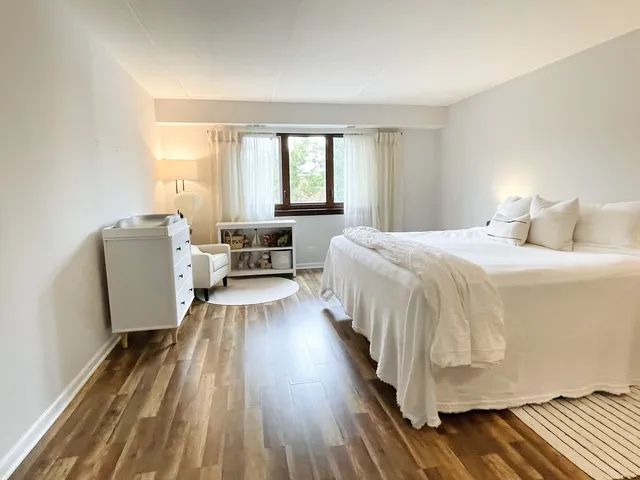 a spacious bedroom with a bed and wooden floor