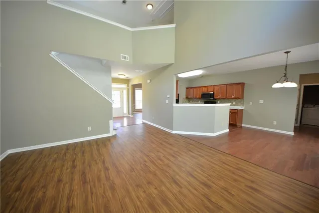 a view of a big room with wooden floor and a kitchen