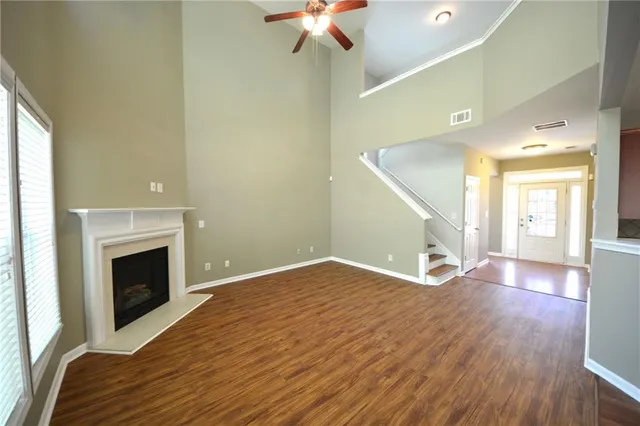 a view of an empty room with wooden floor fireplace and a window