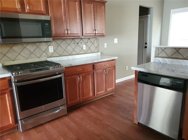 a kitchen with granite countertop cabinets stainless steel appliances and wooden floor