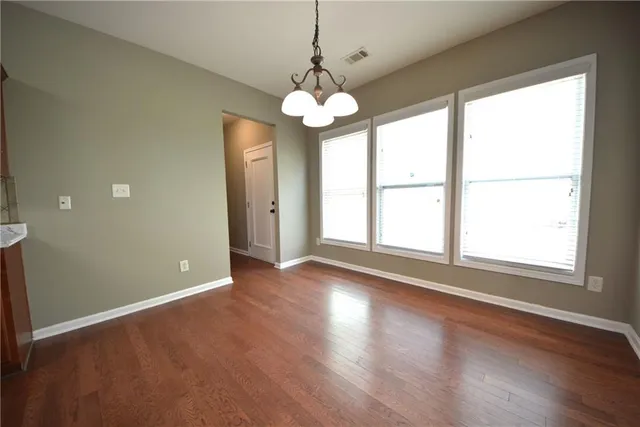 an empty room with wooden floor chandelier and window