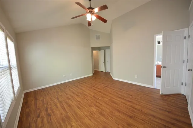 a view of empty room with wooden floor and fan