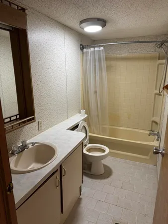 a bathroom with a granite countertop sink toilet and shower
