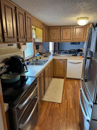 a kitchen with a sink a stove cabinets and a wooden floor