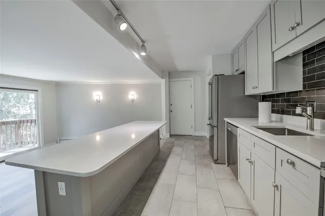 a kitchen with a sink a counter top space stainless steel appliances and cabinets