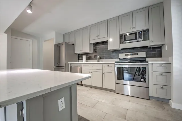 a kitchen with stainless steel appliances a stove microwave and sink