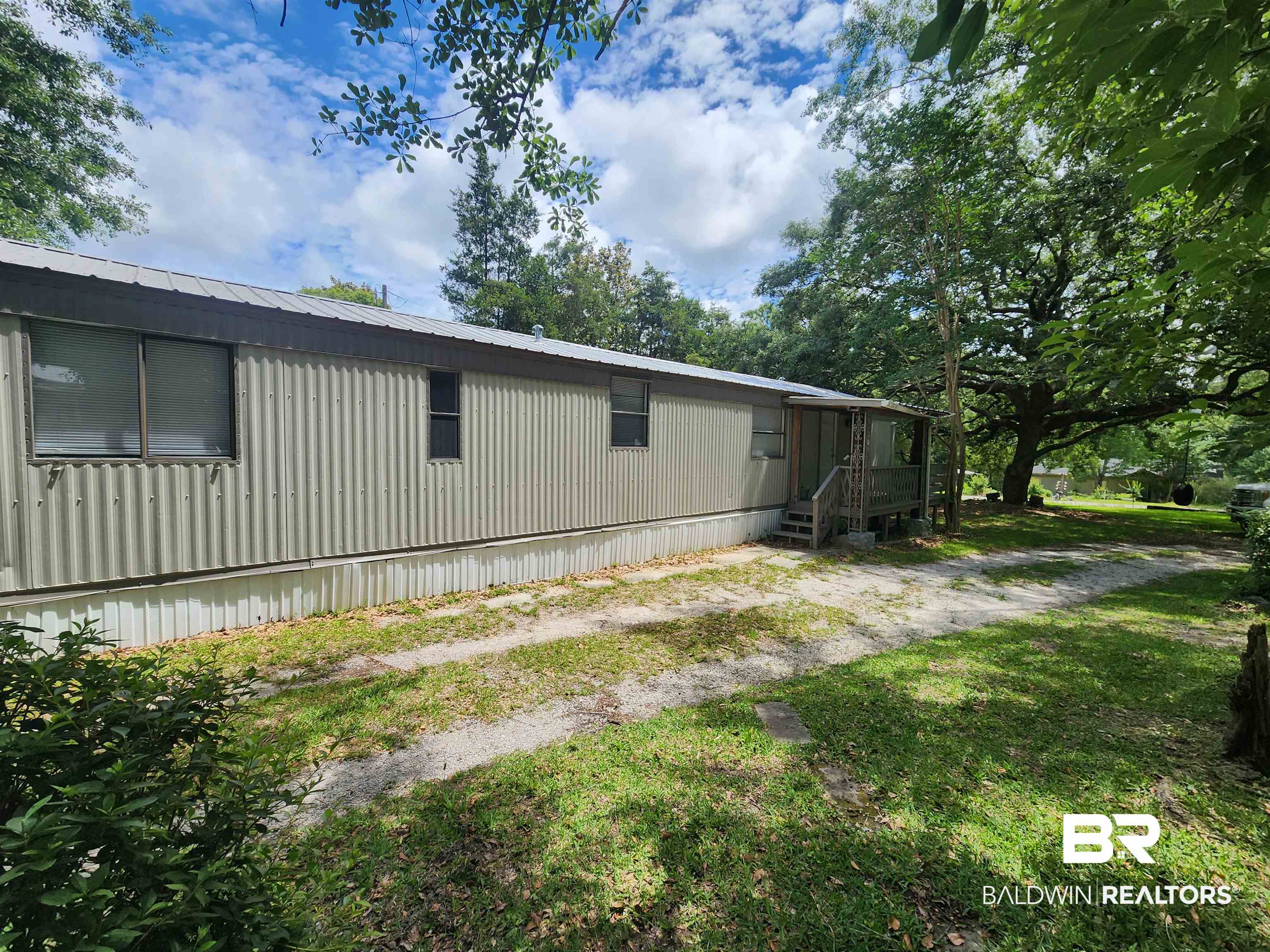 23051 Fritz Lane Foley, AL 36535 - Photo 8 of 26 Single-story residence featuring a corrugated metal exterior, covered front porch, and a gravel driveway