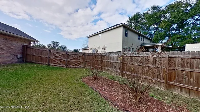 a view of a backyard with wooden fence and a bench