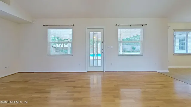 a view of an empty room with wooden floor and a window