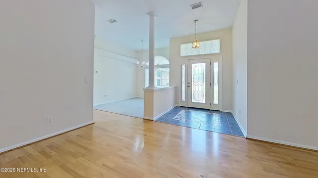 a view of an empty room with window and wooden floor