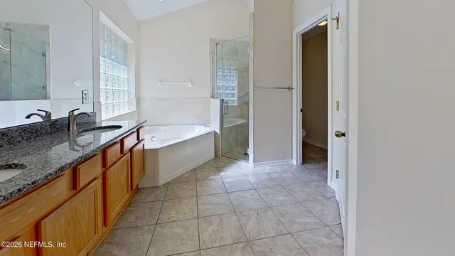 a large bathroom with a granite countertop tub a sink and a large mirror