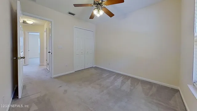 an empty room with a ceiling fan and window