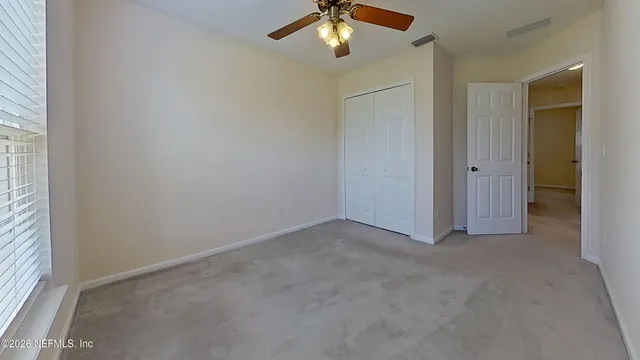 an empty room with a window and a fan