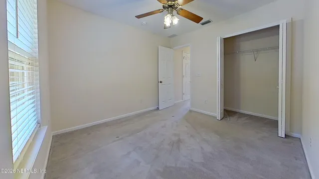 an empty room with a window and a fan