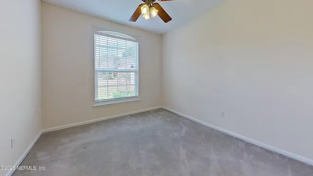 an empty room with a window and a ceiling fan
