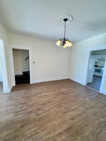 a view of a room with wooden floor chandelier and windows