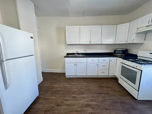 a kitchen with granite countertop white cabinets and white appliances