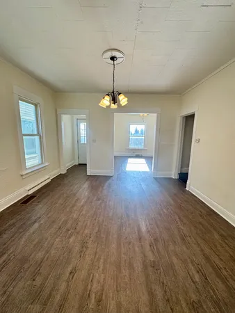 a view of a room with wooden floor chandelier and windows
