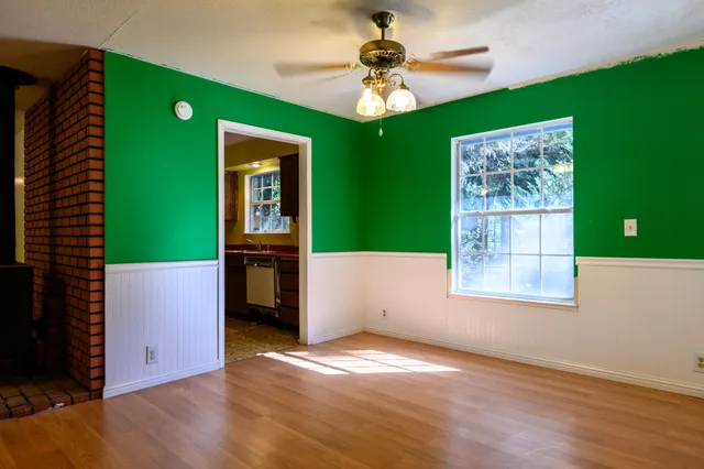 an empty room with wooden floor fan and windows
