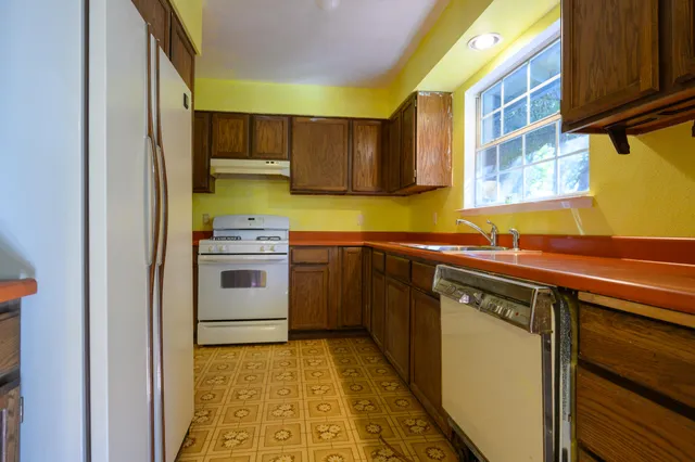 a kitchen with a sink cabinets stainless steel appliances and a window