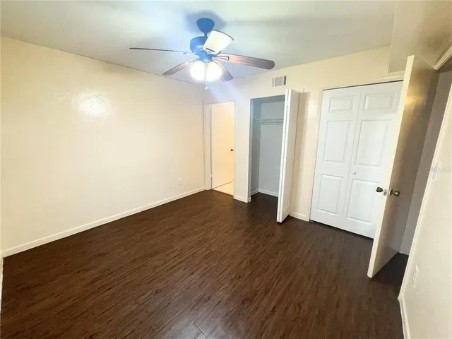 an empty room with wooden floor and a ceiling fan