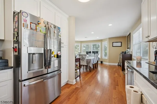 a kitchen with stainless steel appliances a refrigerator a stove and a dining table with wooden floor