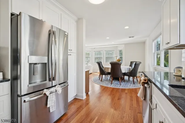 a kitchen with stainless steel appliances granite countertop a refrigerator a stove a sink dishwasher a dining table and chairs with wooden floor