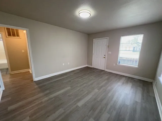 an empty room with wooden floor and windows