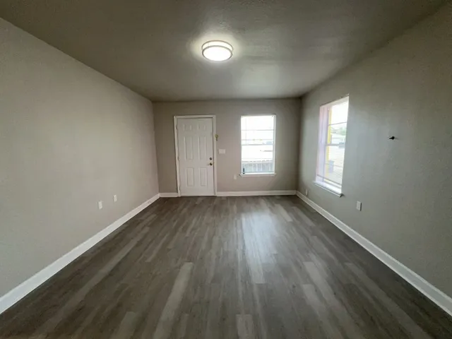 an empty room with wooden floor and windows
