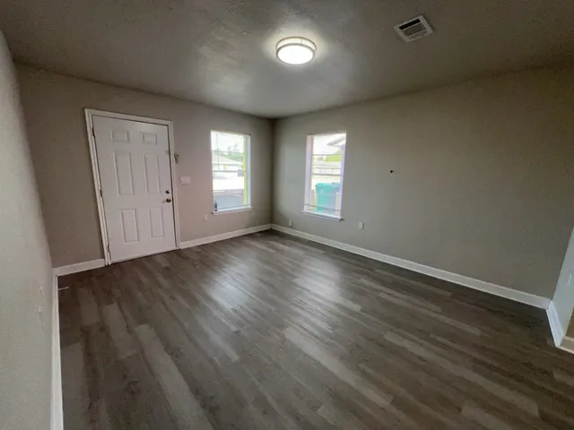 an empty room with wooden floor and windows