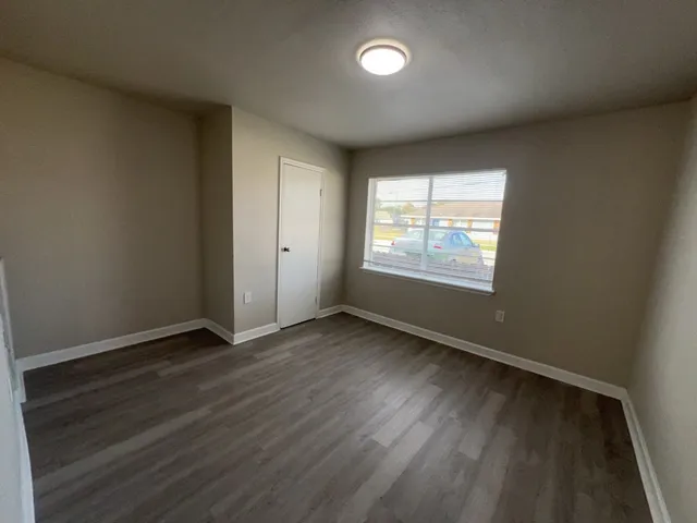 an empty room with wooden floor and windows