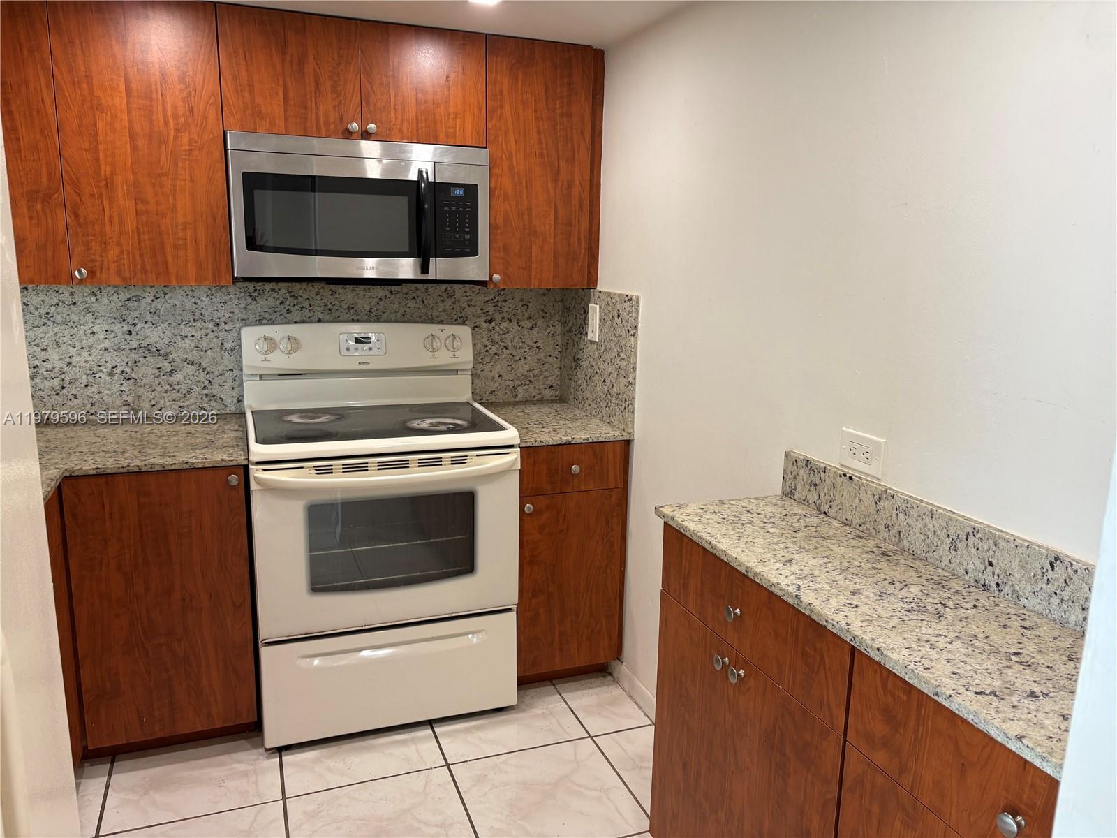 11800 Southwest 18th Street, Unit 5174 Miami, FL 33175 - Photo 7 of 22 a kitchen with granite countertop a stove microwave and sink