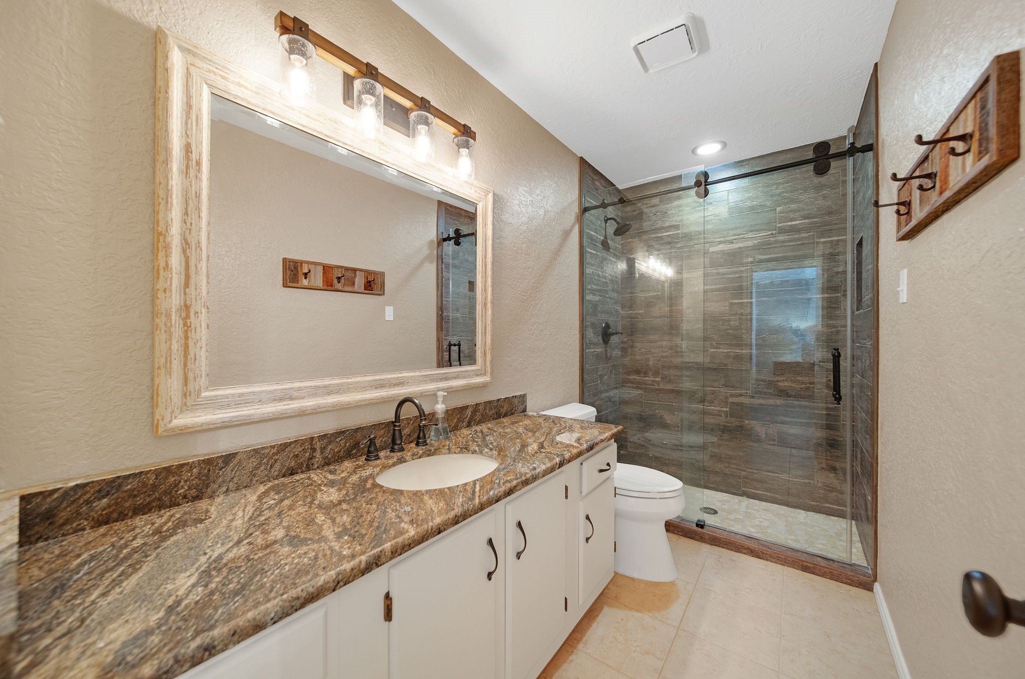 801 River Road, Unit E 116 Montgomery, TX 77356 - Photo 7 of 14 a bathroom with a granite countertop sink a mirror a shower and a toilet