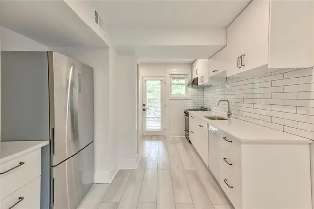 a large white kitchen with a sink and refrigerator