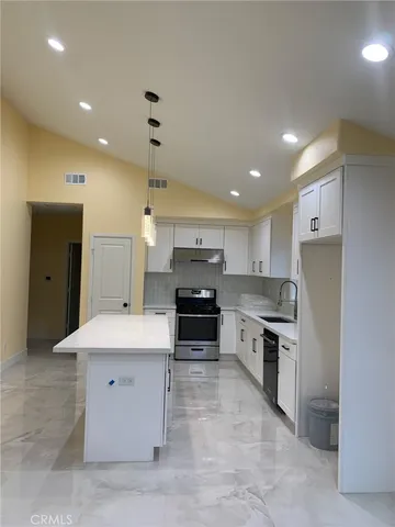 a large kitchen with a large counter top stainless steel appliances and cabinets