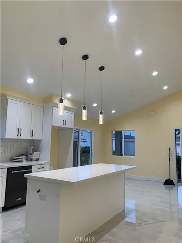 a large kitchen with granite countertop a stove a sink a refrigerator and a dining table with wooden floor