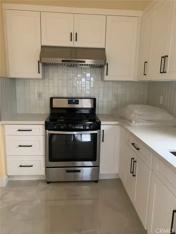 a kitchen with stainless steel appliances granite countertop a stove and a white cabinets