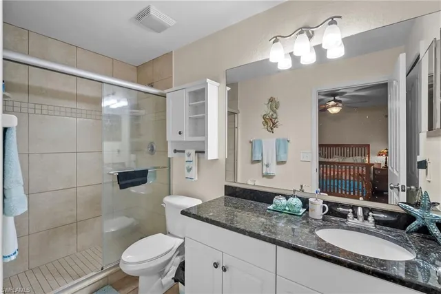 a bathroom with a granite countertop sink toilet a mirror a vanity and shower