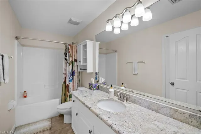 a bathroom with a granite countertop sink a toilet and a mirror