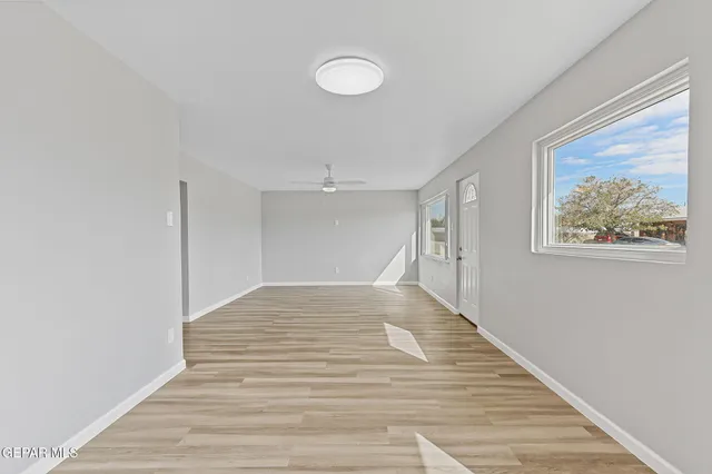 a view of an empty room with wooden floor and a window