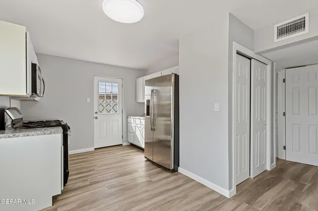 a kitchen with granite countertop cabinets stainless steel appliances and wooden floor