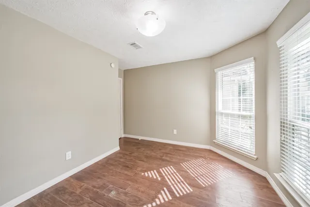 a view of an empty room with a window and wooden floor