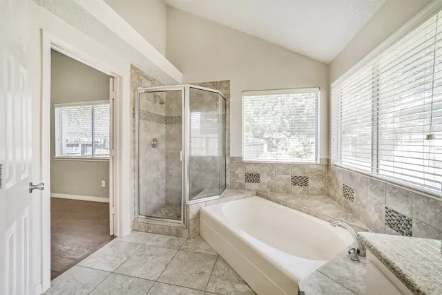 a large bathroom with a granite countertop tub a double vanity sink a mirror and a large window